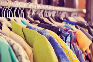 some used clothes hanging on a rack in a flea market